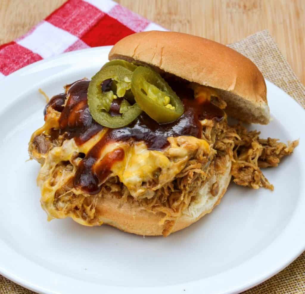 Pulled Pork Sandwich Topped With Cheddar Cheese, Jalapenos and BBQ Sauce