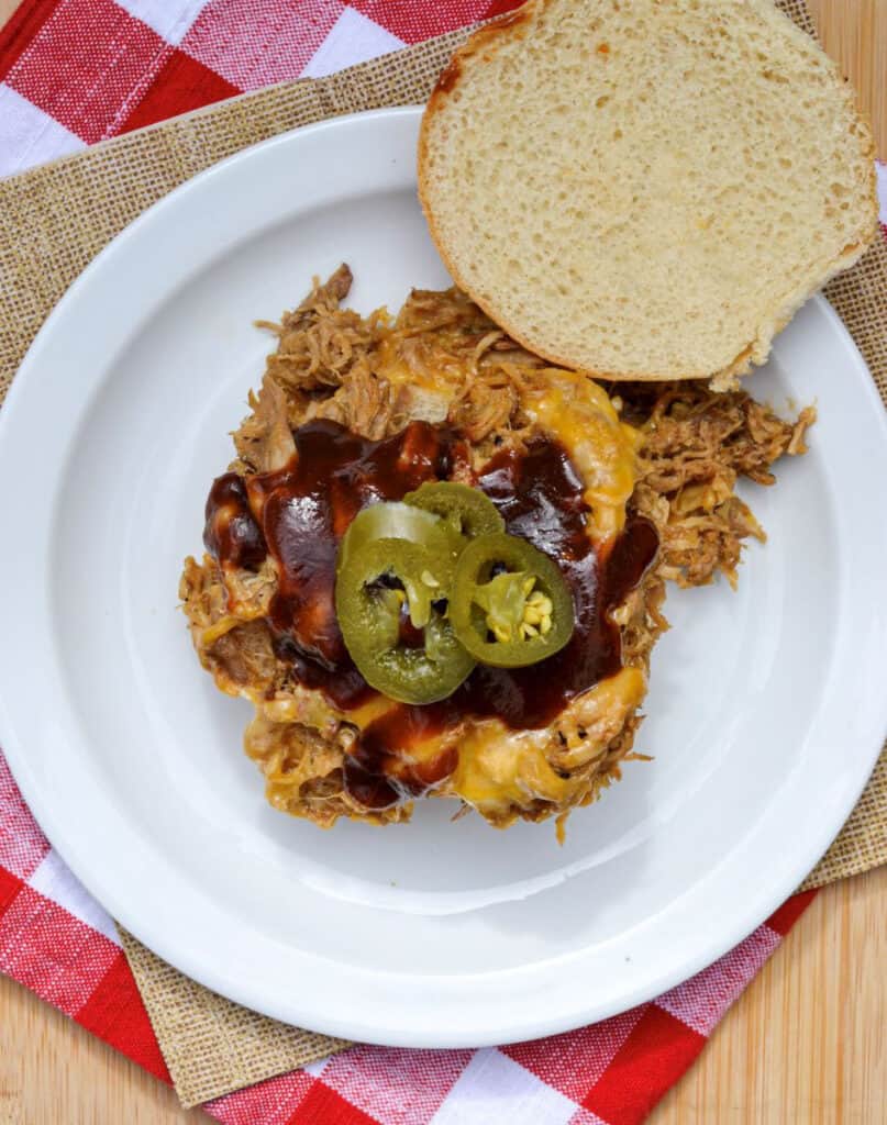 Pulled Pork Sandwich Topped With Cheddar Cheese, Jalapenos and BBQ Sauce